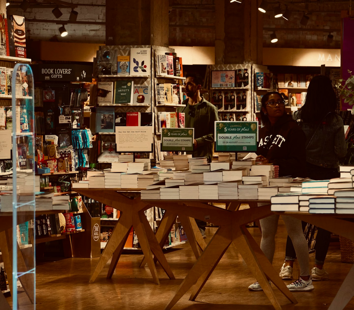 People browsing books in a busy, well-stocked bookstore.