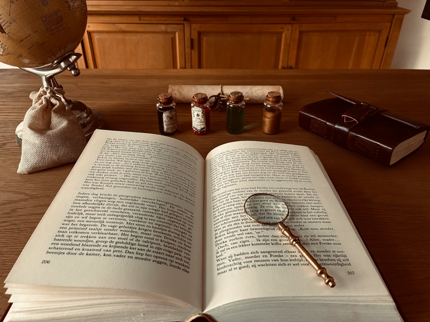 A magnifying glass rests on an open book upon a desk.